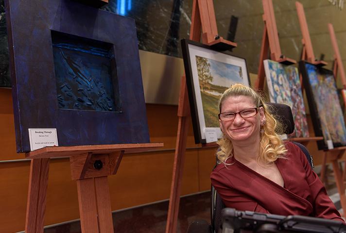 Artist Dorinda Tveit poses in front of her piece titled, "Breaking Through" during an art show at the Diana E. Murphy U.S. Courthouse in Minneapolis.