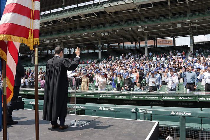 U.S. District Judge John Z. Lee of the Northern District of Illinois leads new citizens in reciting the Oath of Allegiance at Wrigley Field. Photo credit: Jim Slonoff