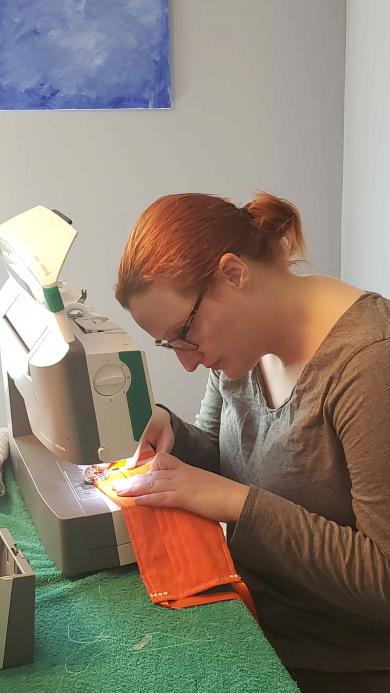 Law Clerk Sarah Tomlinson at home sewing a face mask to help homeless veterans.