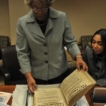 Judge Lewis examines the restored book containing various court records from the Danish colony. 
