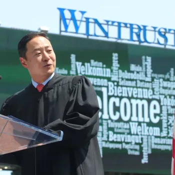 The word “Welcome” displays in several languages on the left field video screen behind U.S. District Judge John Z. Lee of the Northern District of Illinois. Photo credit: Jim Slonoff