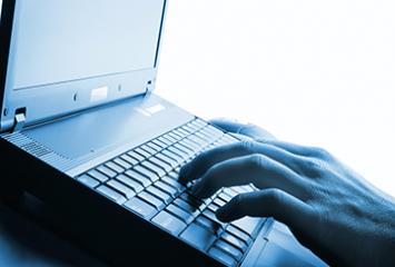 An image of a hand typing on a laptop computer.