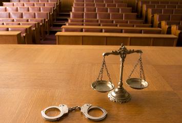 image of handcuffs and scales of justice on a court bench