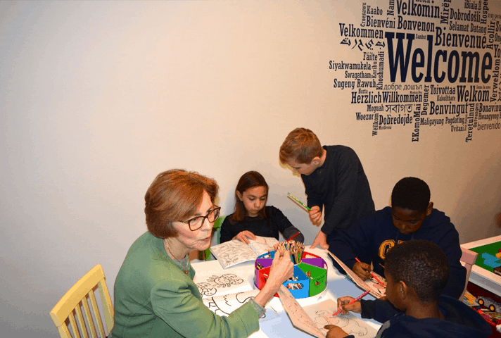 Chief Judge Rebecca R. Pallmeyer joins youngsters at a table with coloring books.