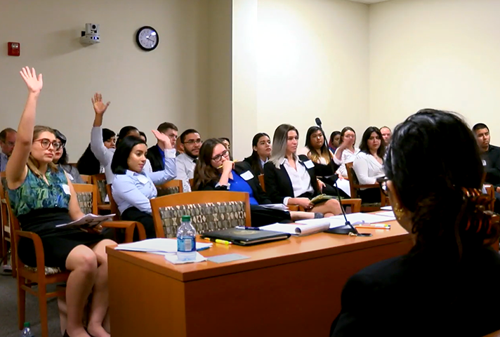 Students in a classroom raising hands as part of a discussion.