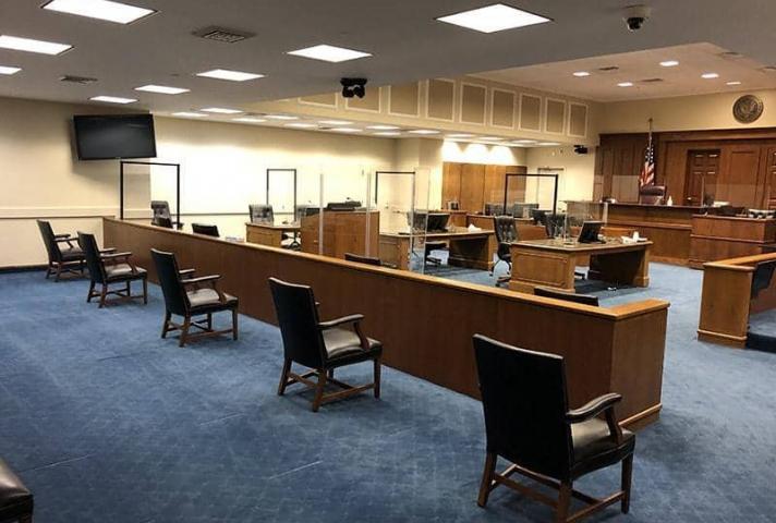 In a Baltimore courtroom, plexiglass divides the parties and court staff, and juror chairs are being kept at a safe social distance.