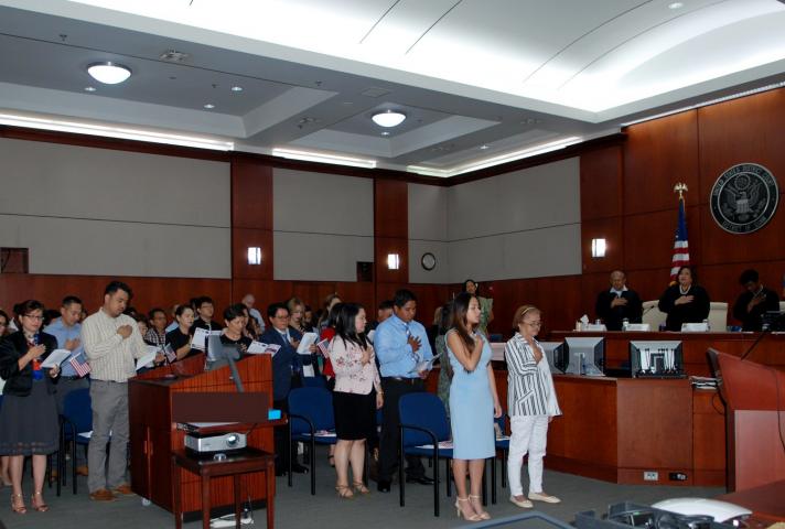 Naturalization ceremony attendees in Guam say the pledge of allegiance.
