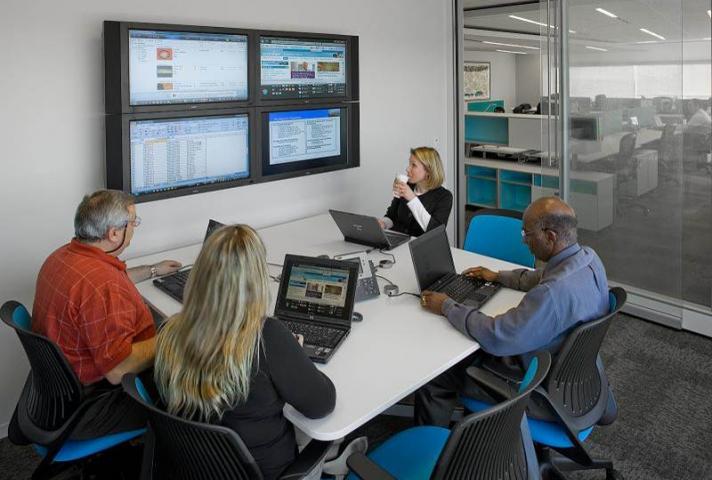 Glass-enclosed meeting rooms can be smaller, while maintaining an open feel. Here, a meeting is held at an office of Accenture, a consulting firm that has assisted on the Integrated Workplace Initiative.