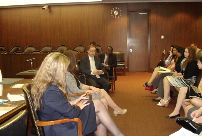 Image of public defenders speaking to teens in a courtroom