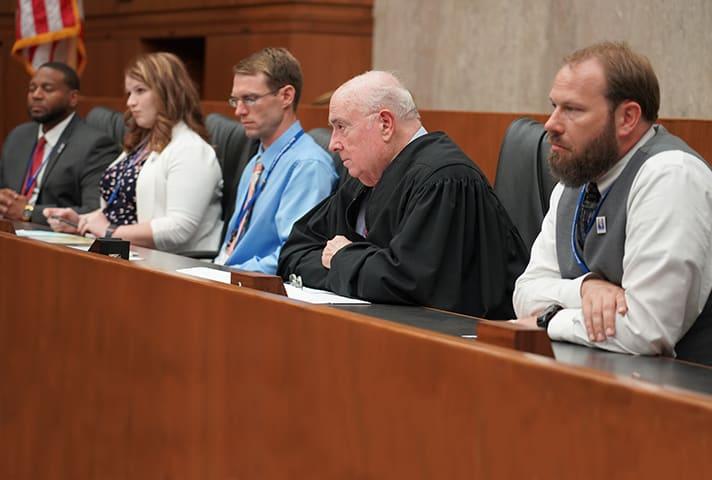 A federal judge shares the bench with teachers during a courtroom simulation.