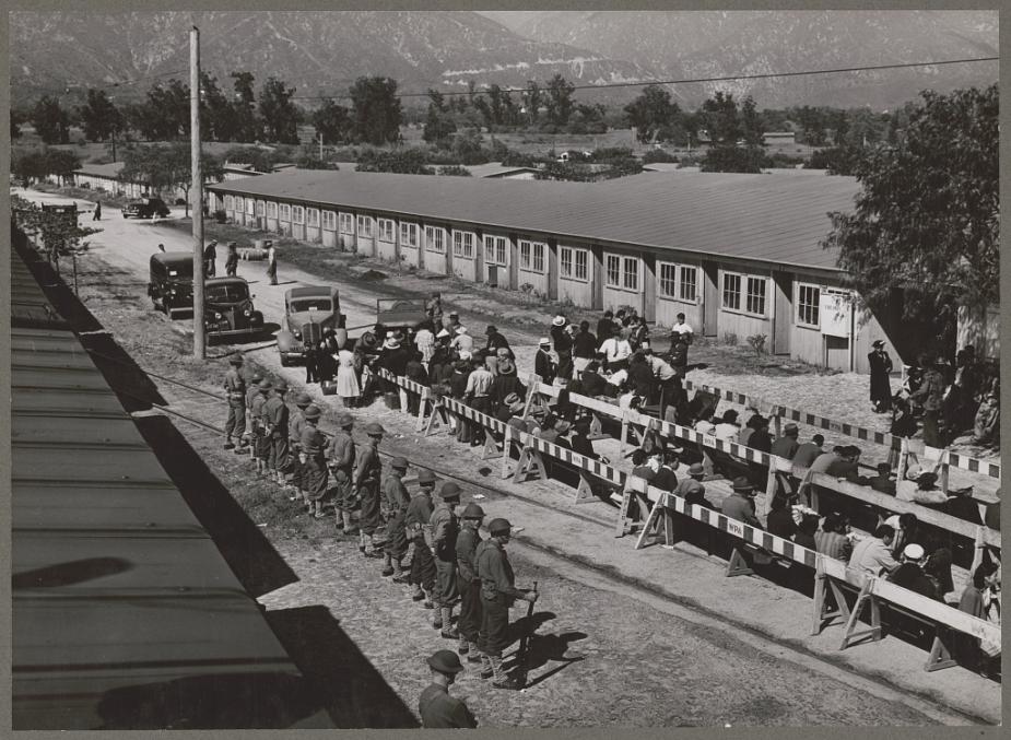 Japanese Americans are guarded at Santa Anita registration center. Uncleaned horse stables at the Southern California racetrack were used for temporary housing.