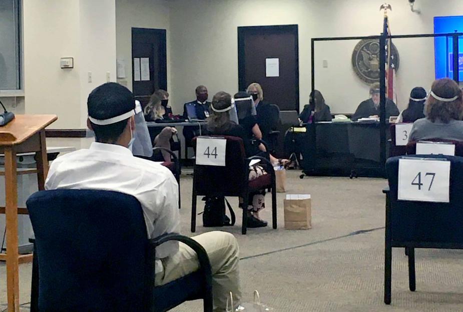 Socially distanced prospective jurors wait their turn during the jury selection process. Judge Lynn and the attorneys are seated at the front of the room behind plexiglass.